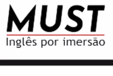 Estudante sorrindo enquanto estuda inglês online em um laptop com materiais de curso.